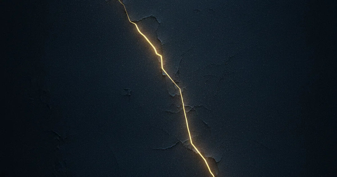 Fenditura dorata che attraversa una parete di pietra scura, luce che filtra da una crepa non del tutto sanata