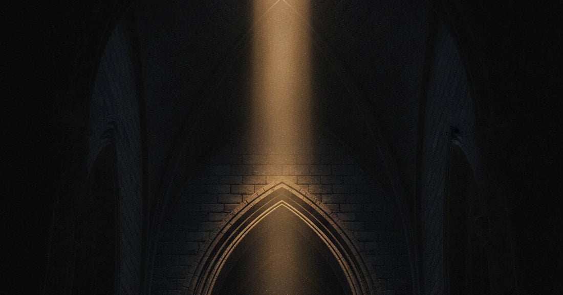 Volta di pietra in penombra con la chiave di volta illuminata da un raggio di luce dorata.